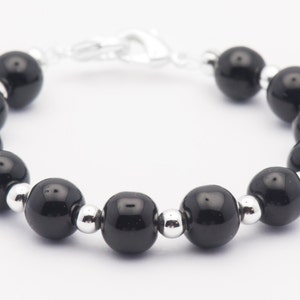 May include: A black beaded bracelet with silver spacers. The bracelet has a silver clasp.