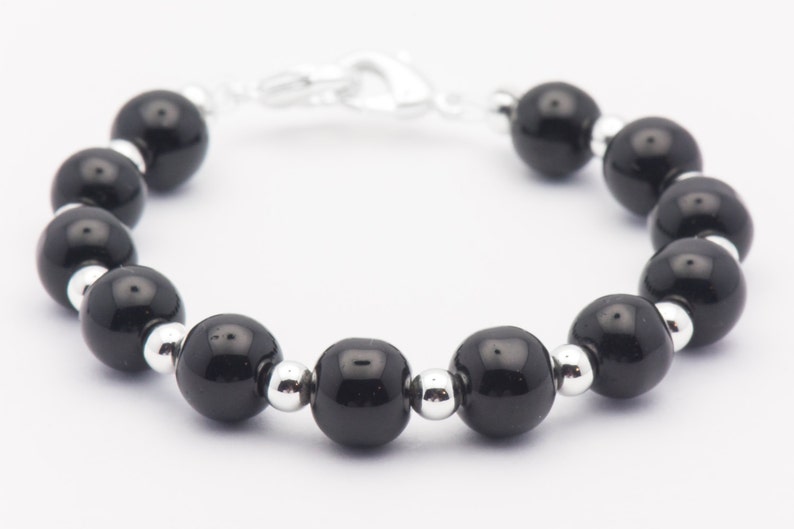 May include: A black beaded bracelet with silver spacers. The bracelet has a silver clasp.