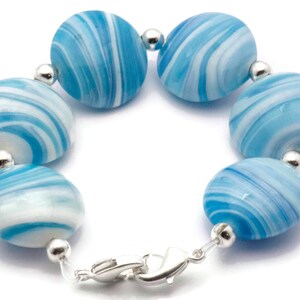 May include: A bracelet made of blue and white swirled glass beads with silver accents and a silver clasp.