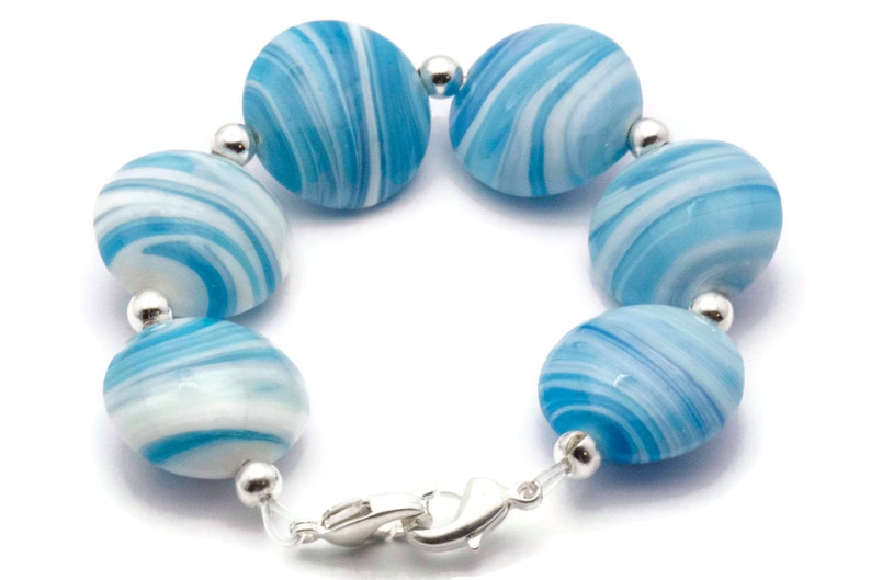 May include: A bracelet made of blue and white swirled glass beads with silver accents and a silver clasp.