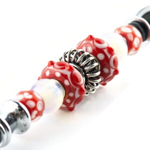 Peut inclure: Un bracelet de charme perl&eacute; argent&eacute; et rouge avec une perle d'espacement argent&eacute;e. Les perles sont rouges avec des pois blancs.