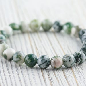 May include: A green and white agate stone bracelet with round beads. The bracelet is made of natural stones and is a beautiful and unique piece of jewelry.