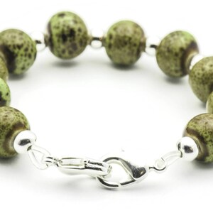 May include: A green and brown speckled bead bracelet with a silver clasp.