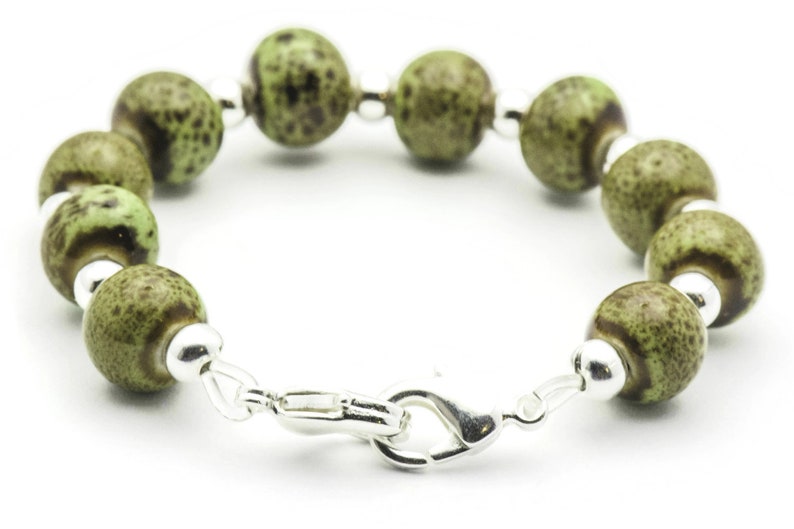 May include: A green and brown speckled bead bracelet with a silver clasp.