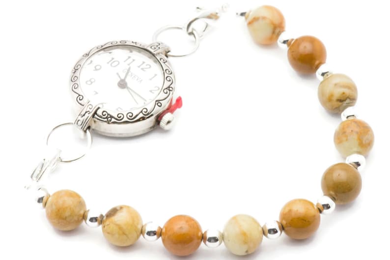 May include: A silver watch with a white face and black hands attached to a brown and white beaded bracelet.