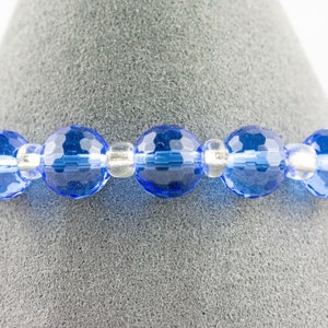 Pu&ograve; includere: Un braccialetto di perline di cristallo blu con perline distanziatrici argentate.