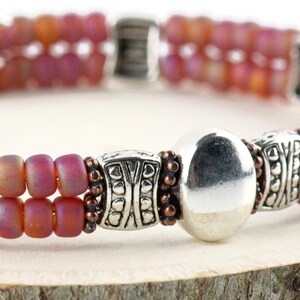 Button and Bows Raspberry Sorbet Cuff Memory Wire Bracelet close up on a wood piece with tree bark edging