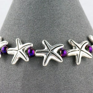 May include: A silver bracelet with purple beads and silver starfish charms.