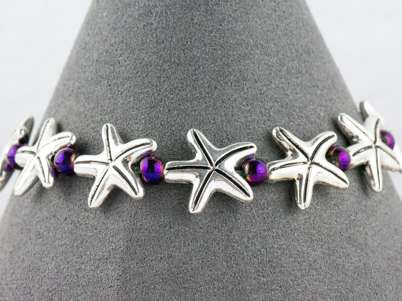 May include: A silver bracelet with purple beads and silver starfish charms.