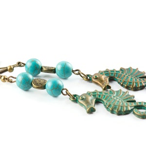 May include: A pair of turquoise and bronze earrings featuring seahorse charms and turquoise beads.