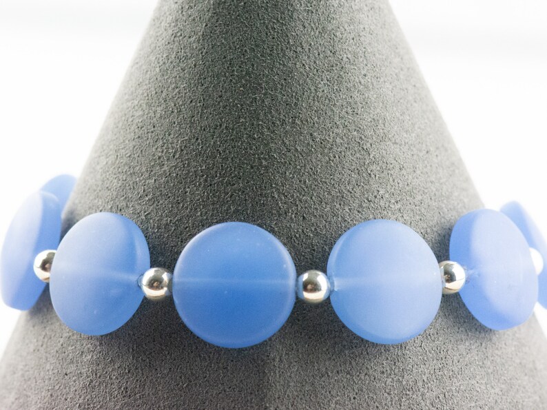Peut inclure: Un bracelet bleu clair compos&eacute; de perles rondes en verre givr&eacute; s&eacute;par&eacute;es par des perles d'espacement argent&eacute;es.