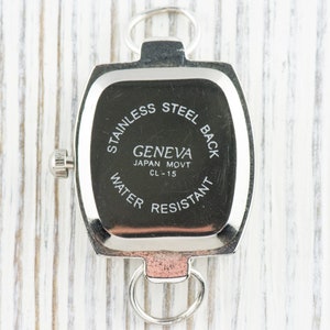 May include: Silver-toned watch back with the text "Stainless Steel Back", "Geneva Japan Movt CL-15", and "Water Resistant".