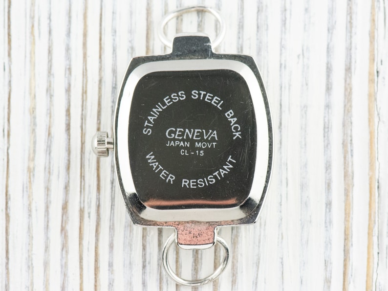 May include: Silver-toned watch back with the text "Stainless Steel Back", "Geneva Japan Movt CL-15", and "Water Resistant".