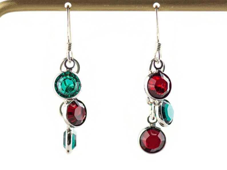 Pu&ograve; includere: Un paio di orecchini pendenti in argento con pietre di cristallo rosse e verdi.