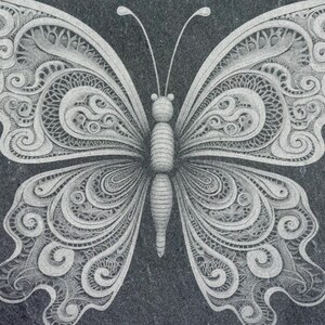 May include: A detailed, intricate, white butterfly design carved into a black slate surface.