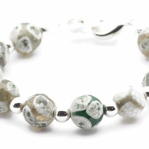 Op de afbeelding: Een armband gemaakt van groene en witte agaat kralen met zilveren tussenstukken. De armband heeft een zilveren sluiting.