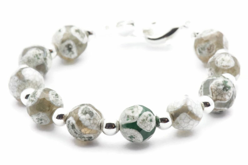 Op de afbeelding: Een armband gemaakt van groene en witte agaat kralen met zilveren tussenstukken. De armband heeft een zilveren sluiting.
