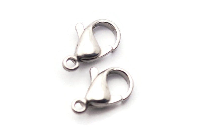 May include: Two silver-toned lobster claw clasps for jewelry making. The clasps are made of metal and have a shiny finish.