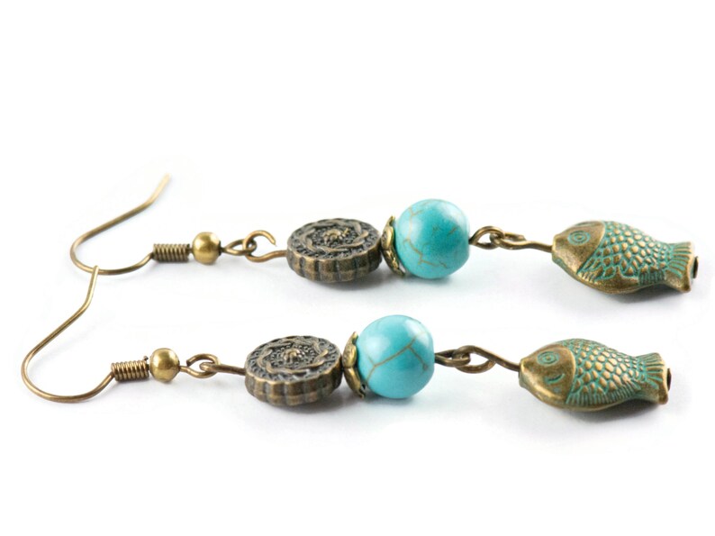 May include: A pair of bronze earrings with turquoise beads and fish charms. The earrings have a hook closure.