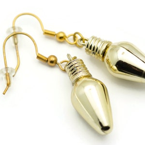 Puede incluir: Un par de pendientes de color dorado con forma de bombilla. Los pendientes tienen un dise&ntilde;o sencillo y elegante, perfectos para a&ntilde;adir un toque de brillo a cualquier atuendo.