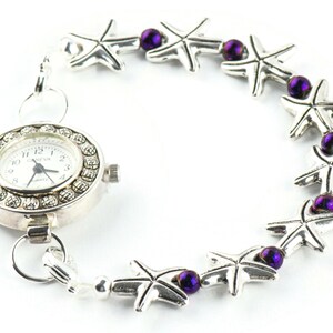 May include: A silver watch with a white face and a silver chain with purple beads and silver starfish charms.
