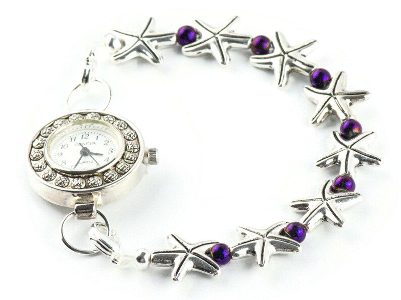 May include: A silver watch with a white face and a silver chain with purple beads and silver starfish charms.