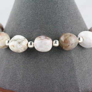 May include: A bracelet made of white and brown agate beads with silver spacers.