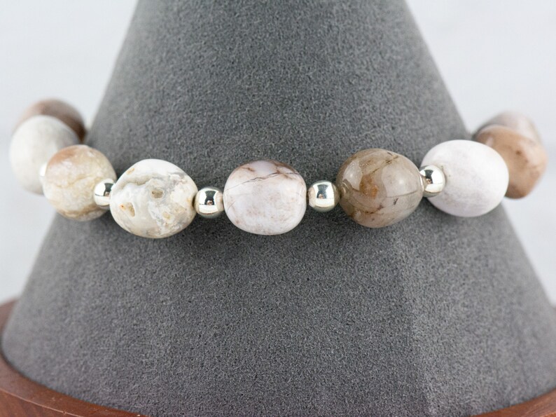 May include: A bracelet made of white and brown agate beads with silver spacers.