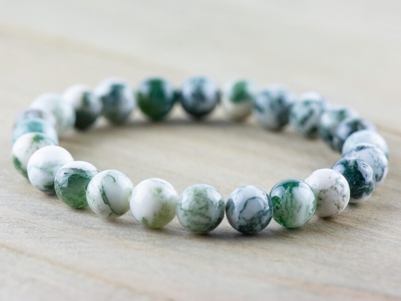 May include: A green and white agate beaded bracelet. The beads are round and have a natural, marbled pattern.