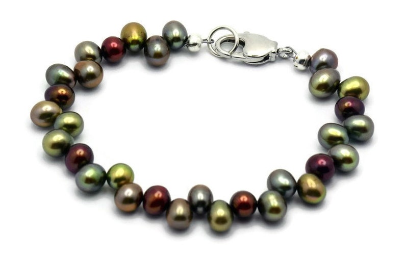 Puede incluir: Un brazalete de perlas de agua dulce multicolores con un cierre plateado. Las perlas son una mezcla de verde, marr&oacute;n y negro.