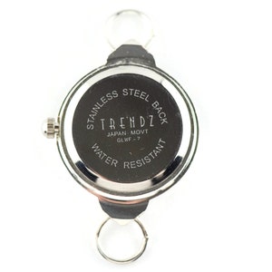 Peut inclure: Dos d'une montre argent&eacute;e avec un cadran noir. Le cadran de la montre indique "Stainless Steel Back", "Trendz", "Japan Movt", "GLWF - 7", et "Water Resistant".