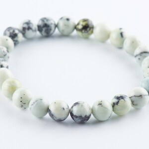 May include: A white and black speckled stone bracelet with a round shape. The bracelet is made of natural stones and is a popular choice for jewelry.