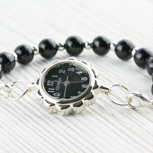 May include: A black beaded bracelet with a silver watch face that says "GENEVA" and has black hands and numbers.