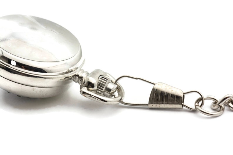 May include: A silver pocket watch with a chain attached. The watch has a round face and a hinged lid.