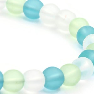 May include: A bracelet made of frosted glass beads in shades of light blue, green, and white.