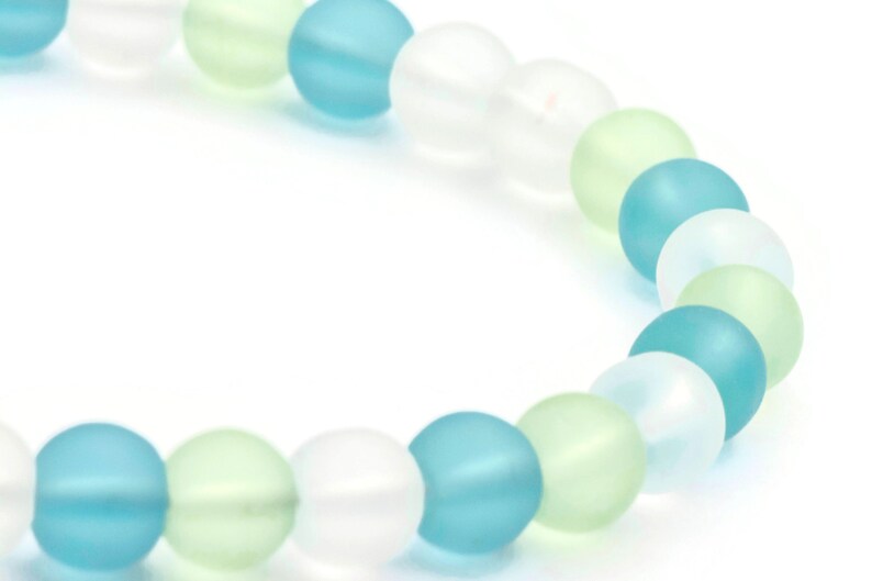 May include: A bracelet made of frosted glass beads in shades of light blue, green, and white.