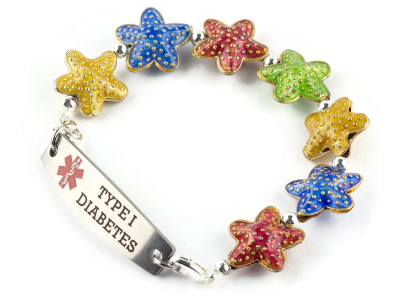 Puede incluir: Una pulsera colorida con una etiqueta de alerta m&eacute;dica que dice "TYPE I DIABETES". La pulsera tiene una cadena plateada con un s&iacute;mbolo m&eacute;dico rojo y una serie de abalorios de estrella de mar de colores.