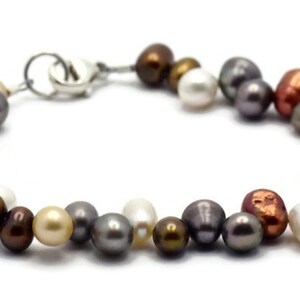 May include: A multi-colored freshwater pearl bracelet with a silver clasp. The pearls are in shades of white, cream, gray, brown, copper, and blue.