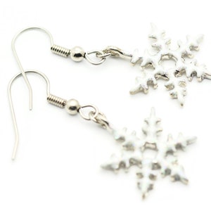 May include: A pair of silver snowflake dangle earrings. The earrings have a simple hook closure and a silver snowflake charm.