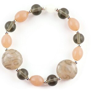 May include: A bracelet featuring alternating light pink and dark grey beads. The bracelet includes two larger, round, grey beads with a swirling pattern.