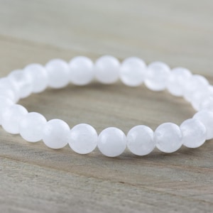 May include: White gemstone bracelet with round beads. The bracelet is made of natural white stones and is a simple and elegant piece of jewelry.