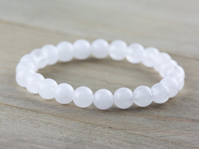 May include: White gemstone bracelet with round beads. The bracelet is made of natural white stones and is a simple and elegant piece of jewelry.