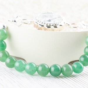 May include: A green gemstone bracelet with a silver clasp and a small silver watch attached.