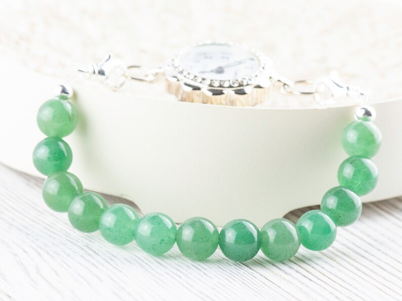 May include: A green gemstone bracelet with a silver clasp and a small silver watch attached.