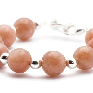May include: A bracelet made of light brown sunstone beads and silver beads. The bracelet has a silver clasp.