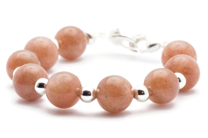 May include: A bracelet made of light brown sunstone beads and silver beads. The bracelet has a silver clasp.