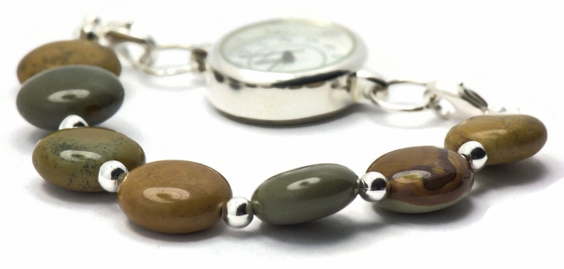 May include: A silver watch with a white face and a brown and green stone bracelet.