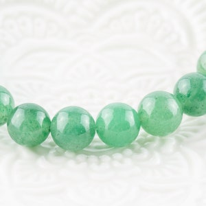 May include: A green gemstone bracelet with round beads.
