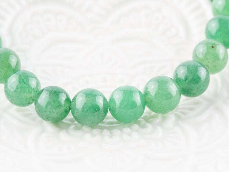 May include: A green gemstone bracelet with round beads.