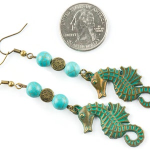 May include: Turquoise and bronze earrings featuring a seahorse charm and turquoise beads. The earrings are approximately the size of a UK 20 pence coin.
